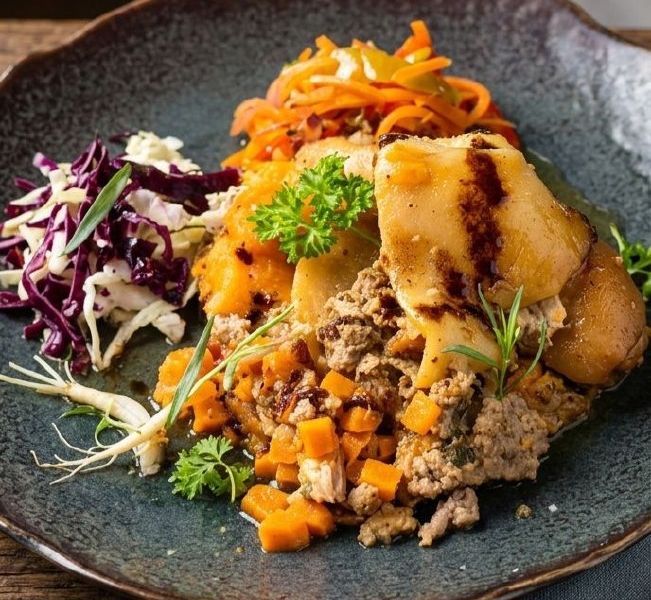 Assiette traiteur dressée : effiloché de viande et légumes, pommes de terre glacées, chou rouge et carottes